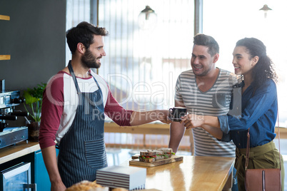 Waiter serving a coffee to customer at counter