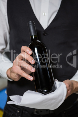 Bartender serving bottle of wine in bar counter