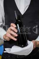 Bartender serving bottle of wine in bar counter