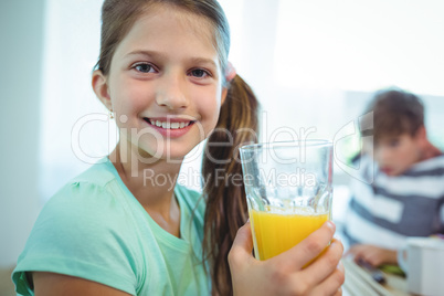 Smiling girl having orange juice