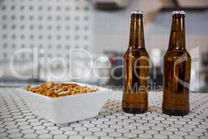 Beer bottles and bowl of snacks on bar counter