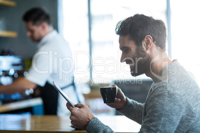 Man using mobile phone while having cup of coffee