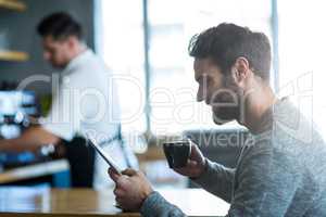 Man using mobile phone while having cup of coffee