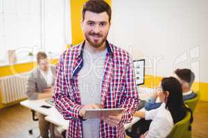 Portrait of confident businessman with tablet at creative office