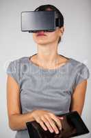 Woman holding digital tablet and using virtual reality headset