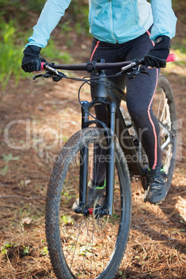 Female mountain biker riding bicycle in the forest