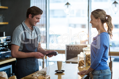 Customer making payment through payment terminal at counter