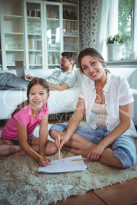 Mother and daughter sitting on the floor and drawing