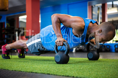 Athlete doing push-ups with kettlebells