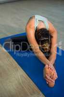 Woman performing head of the knee pose on exercise mat