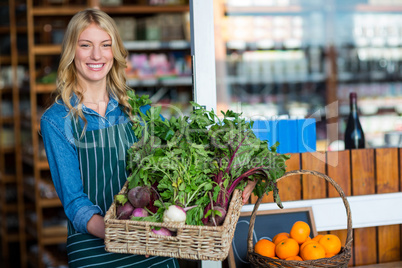 Smiling staff holding a basket of fresh vegetables in organic section