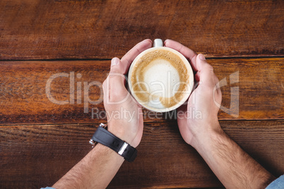 Hands holding a coffee cup on a table