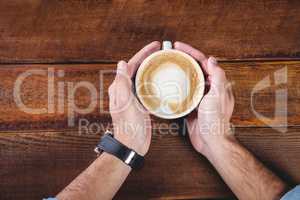 Hands holding a coffee cup on a table