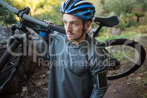 Male mountain biker carrying bicycle in the forest