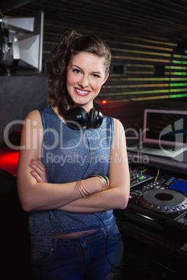 Pretty female DJ standing with arms crossed