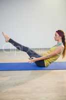 Woman doing navasana yoga pose on exercise mat