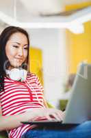 Happy female executive using laptop at creative office