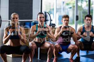 Portrait of friends holding kettlebells in gym