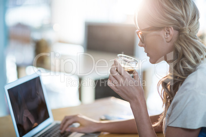 Woman using a laptop while having cup of coffee