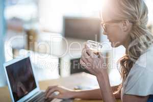 Woman using a laptop while having cup of coffee