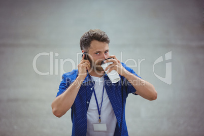 Handsome man drinking coffee while talking on mobile phone