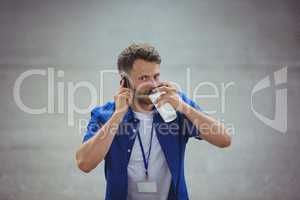 Handsome man drinking coffee while talking on mobile phone