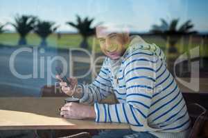 Smiling man using mobile phone in the coffee shop