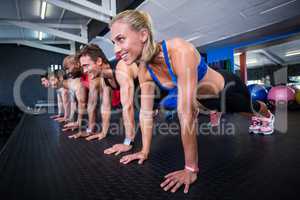 Smiling friends doing push-ups in gym