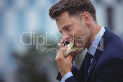 Handsome businessman eating snacks