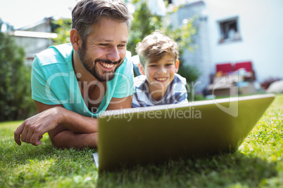 Father and son using laptop in garden