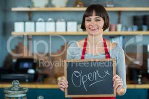 Smiling waitress showing slate with open sign