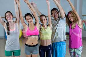 Group of fitness team posing with arms up in fitness studio