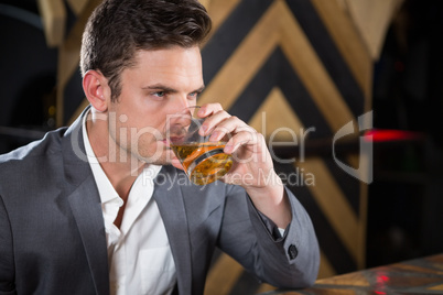 Depressed man having glass of whisky at counter