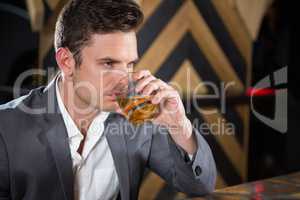 Depressed man having glass of whisky at counter