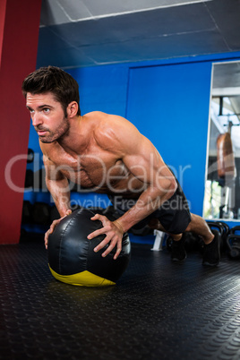 Shirtless athlete exercising with ball