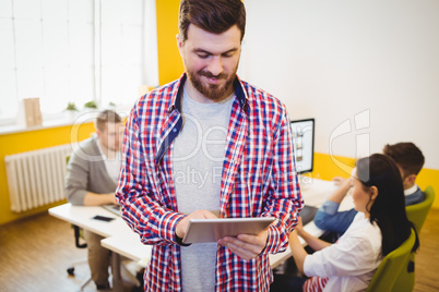 Happy executive using tablet computer at creative office