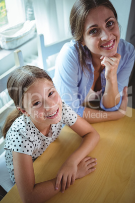 Happy mother and daughter leaning on the table