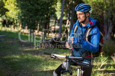 Male mountain holding water bottle standing with bicycle
