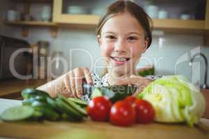 Girl cutting zucchini in kitchen at home
