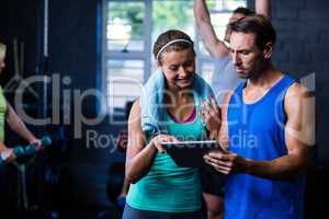 Athletes looking in tablet computer at gym