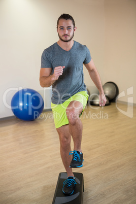 Portrait of serious man doing exercise on aerobic stepper