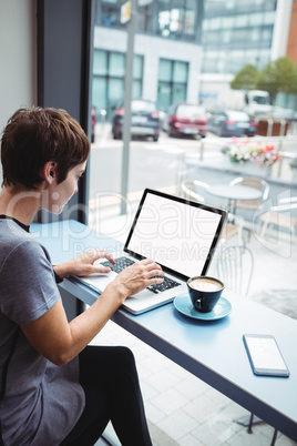 Businesswoman having a cup od coffee while using laptop