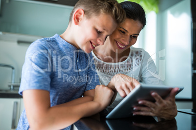 Mother and son using digital tablet in the living room