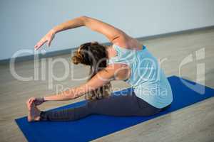 Woman performing head of the knee pose on exercise mat
