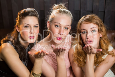 Smiling female friends blowing a kiss towards camera