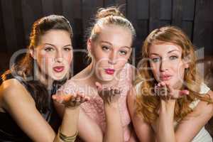 Smiling female friends blowing a kiss towards camera