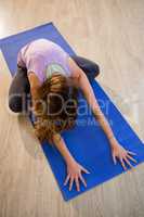 Woman doing cross legged forward fold on exercise mat