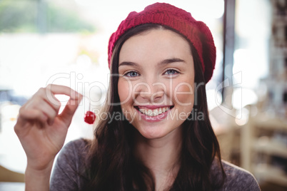Portrait of smiling woman holding cherry