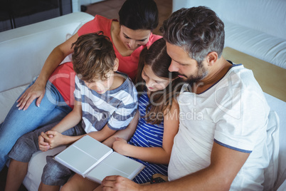 Family sitting on sofa and looking at a photo album