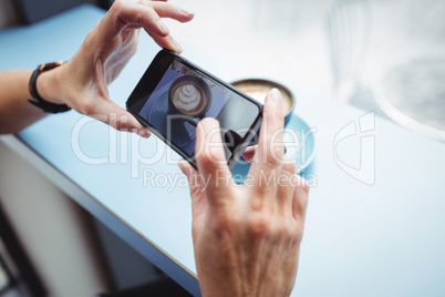 Woman taking photo of a coffee from mobile phone